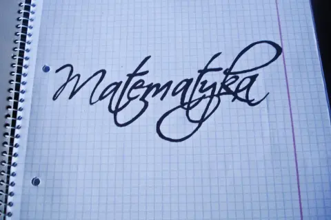 Napis "Matematyka" wykonany ozdobnym pismem odręcznym na kartce w kratkę.